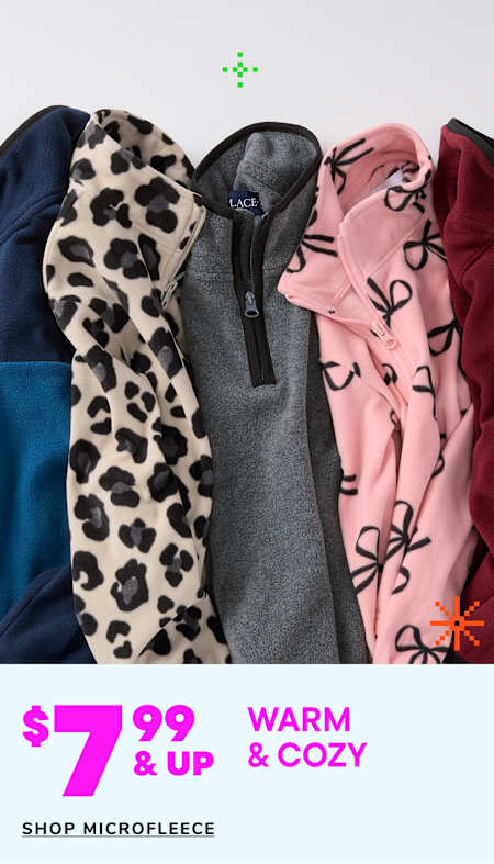 Two young children, a boy and a girl, are wearing matching beige hooded sweatshirts and smiling at each other in a warm and cozy setting.