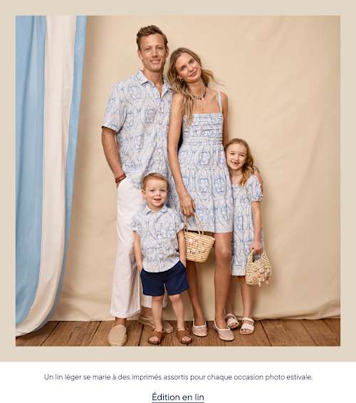 Une famille de quatre personnes, vêtues de tenues assorties à motifs bleu clair, pose devant un fond neutre agrémenté de drapés.