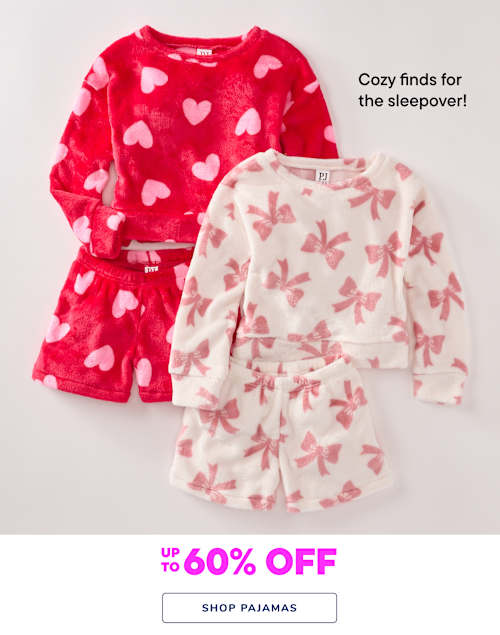 The image shows two pairs of cozy pajamas - one with a red heart pattern and the other with a pink butterfly pattern. The background is a plain white surface, allowing the vibrant colors and patterns of the pajamas to stand out.