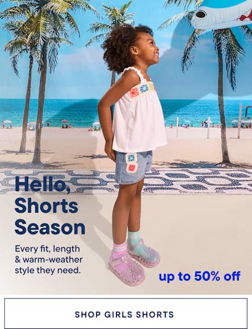 A young girl with curly hair stands on a beach with palm trees in the background, wearing a white top and colorful shorts, promoting a "Shorts Season" sale.