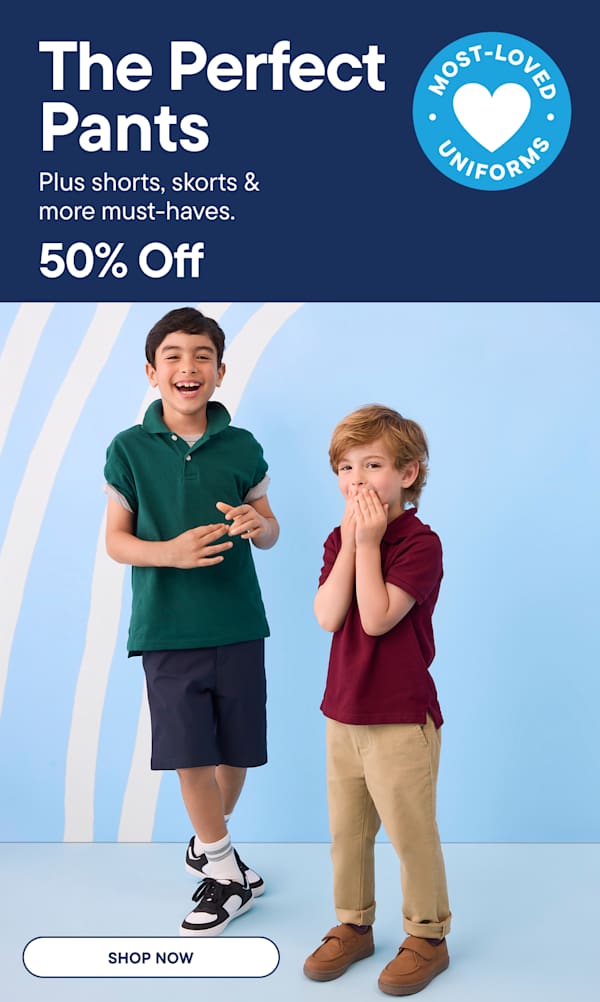 Two young boys in school uniforms smile and pose in front of a light blue background with white stripes.