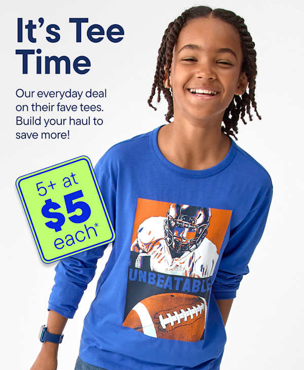 A smiling boy in a blue long-sleeved shirt with a football graphic stands against a light gray background, with a green sign advertising a deal in the foreground.