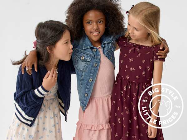 Three young girls in stylish outfits pose together against a plain white background.